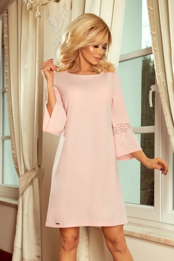 The woman in the photo is wearing a stunning pink lace dress, perfect for elegant occasions. This lace dress showcases intricate detailing and a flattering fit, making it a must-have for any wardrobe.