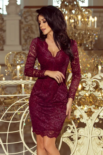 Kobieta na zdjęciu prezentuje elegancką sukienkę koronkową w głębokim odcieniu bordo, która idealnie podkreśla sylwetkę. Sukienka koronkowa z długimi rękawami i delikatnym wzorem dodaje szyku i klasy, idealna na wyjątkowe okazje.