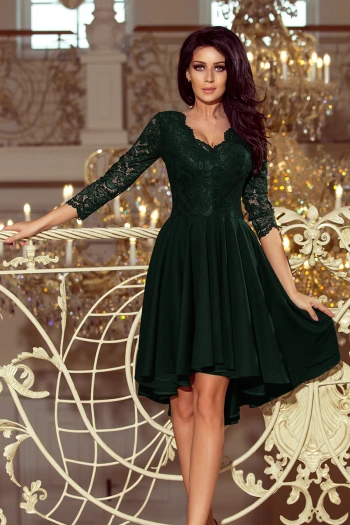 Modelka prezentuje elegancką sukienkę wieczorową z koronkowymi rękawami, która idealnie podkreśla sylwetkę. Ta sukienka wieczorowa w głębokim odcieniu zieleni dodaje klasy i szyku każdej stylizacji.