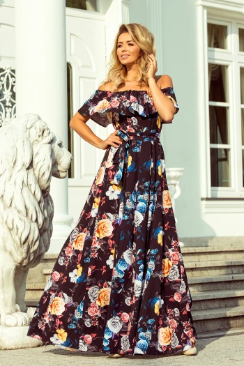 Modelka prezentuje elegancką sukienkę maxi w kwiaty, która idealnie podkreśla kobiecą sylwetkę. Ta kwiecista sukienka maxi z odkrytymi ramionami dodaje stylu i wdzięku, idealna na letnie przyjęcia.