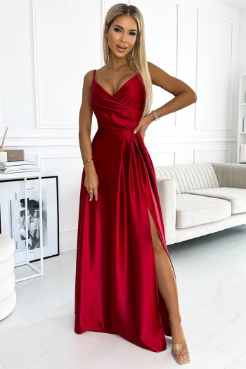 The woman in the photo is wearing a stunning black evening gown with a shimmering finish, perfect for elegant occasions. The gown features a flattering wrap design and a stylish slit, showcasing its sophisticated allure.