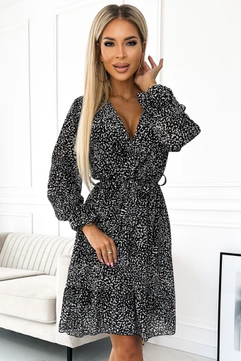 The woman in the photo is wearing a stylish paisley print dress, featuring a deep V-neck and long sleeves. This elegant paisley dress is cinched at the waist with a black belt, highlighting its flattering silhouette.