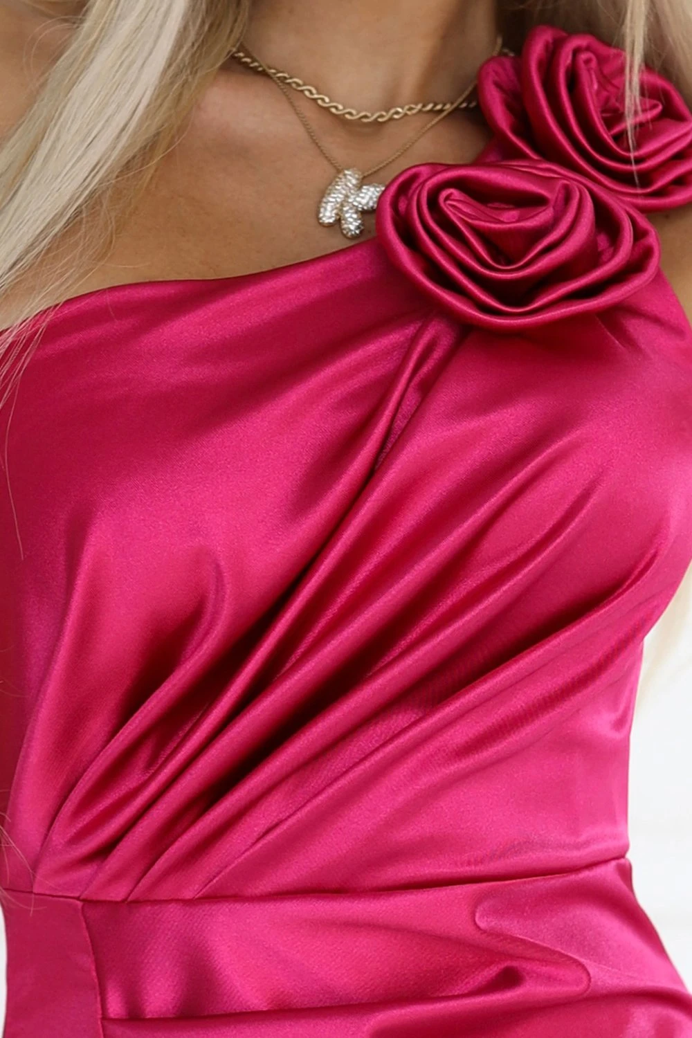 The woman in the photo is wearing a stunning red pleated dress, accentuated by a matching belt that adds a touch of elegance. This chic ensemble highlights the dress's vibrant color and sophisticated design, perfect for any formal occasion.