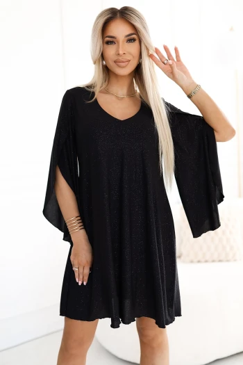 The woman in the photo is wearing a stunning black evening gown with a shimmering finish and a stylish slit. This elegant dress perfectly highlights the allure of formal wear, making it ideal for special occasions.