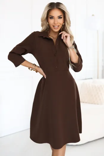 The woman in the photo is wearing a chic brown A-line dress with a button-up front and three-quarter sleeves. This elegant brown dress exudes a sophisticated style perfect for both casual and professional settings.