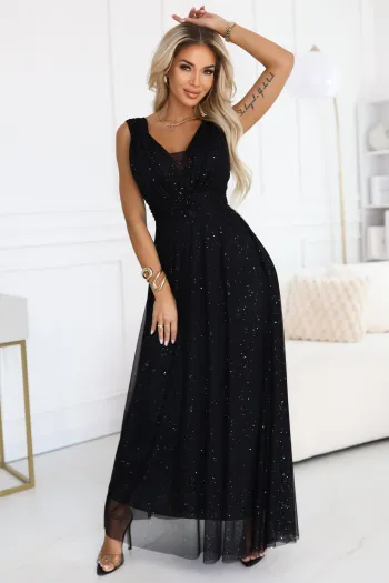 The woman in the photo is wearing a long black evening gown, elegantly designed with subtle sparkles throughout. This floor-length black gown features a sleeveless cut and a fitted waist, perfect for formal occasions.