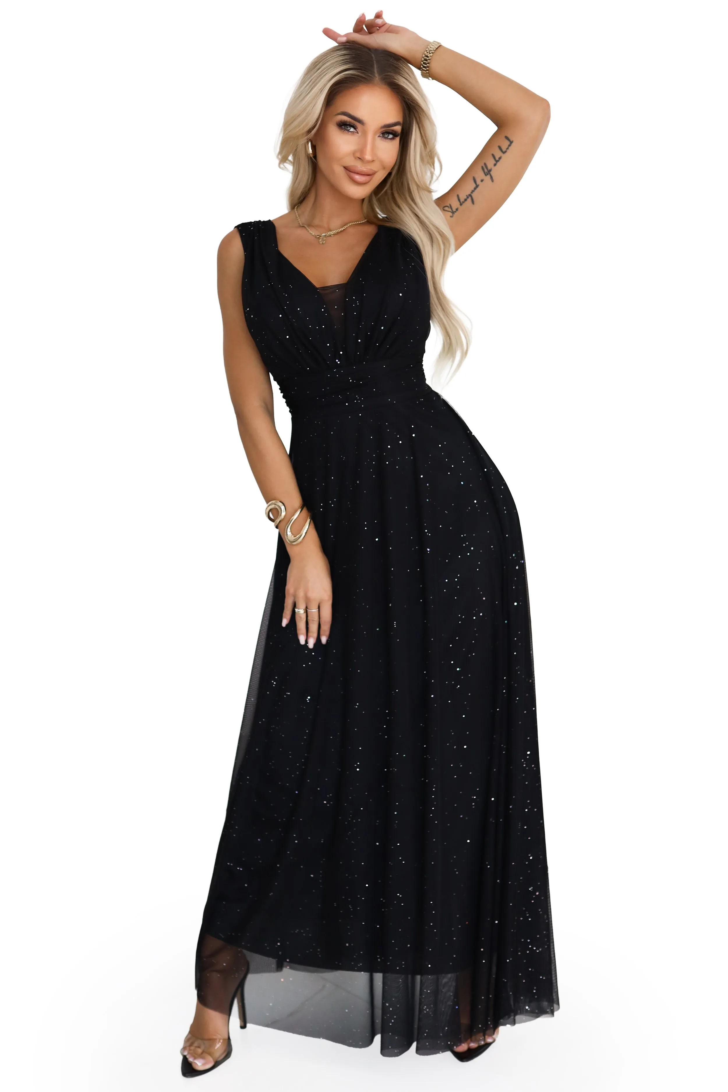 The model showcases a dazzling black floor-length gown embellished with subtle sparkling accents, perfect for evening events. The sleeveless dress features a fitted waist and flowing skirt, highlighting elegance and grace.